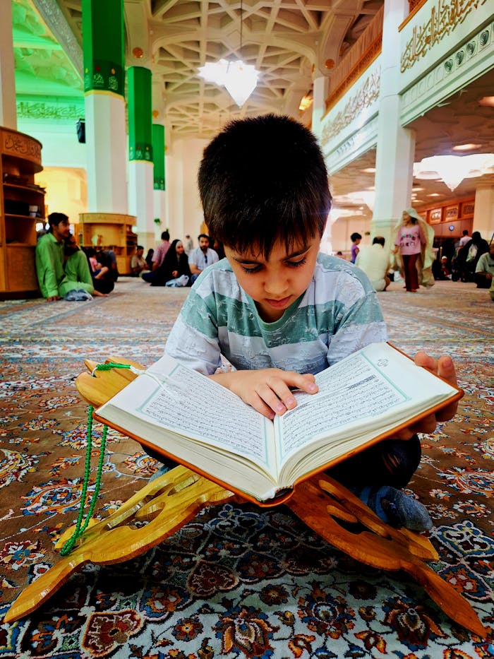 A young boy deeply engrossed in reading the Quran inside a mosque in Qom, Iran.
