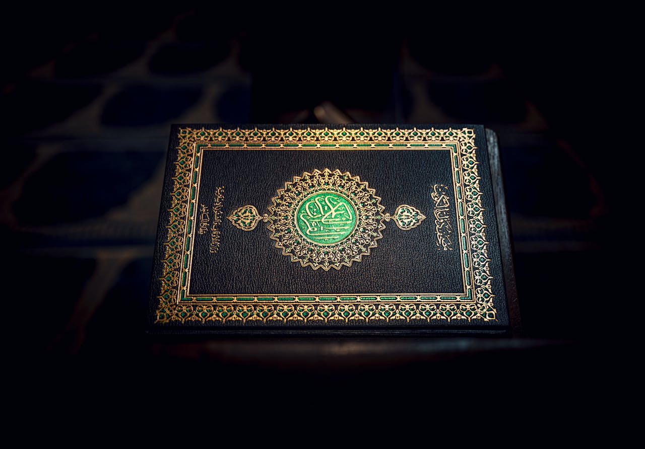 Islamic Holy Quran book with ornate gold detailing, resting on a patterned surface.