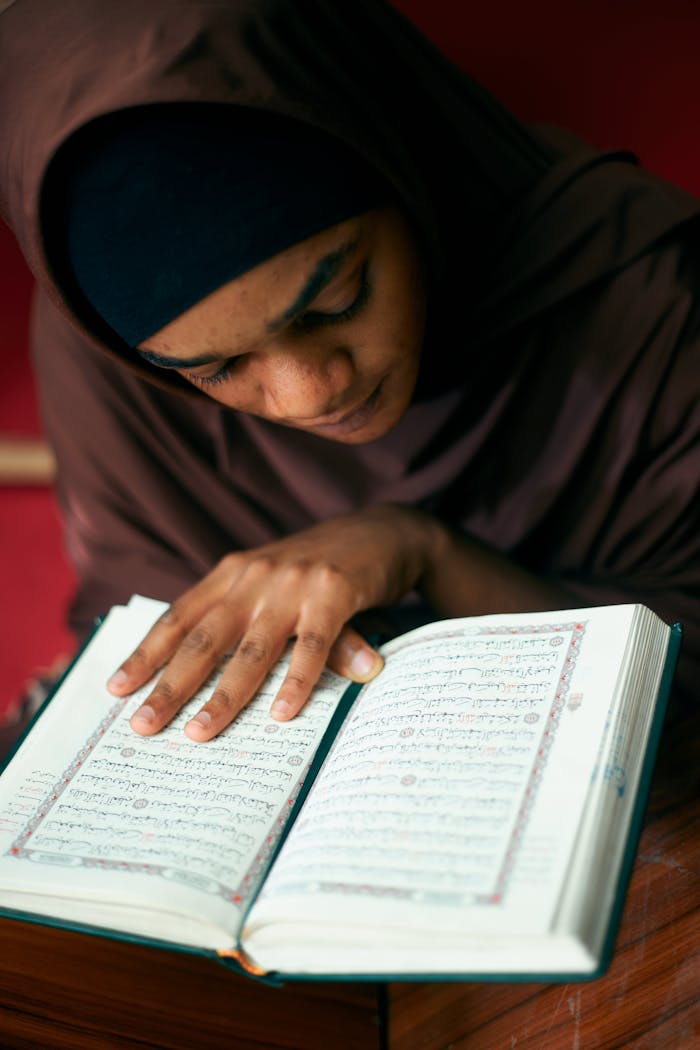 A young woman reading the Quran indoors, showcasing devotion and spirituality.
