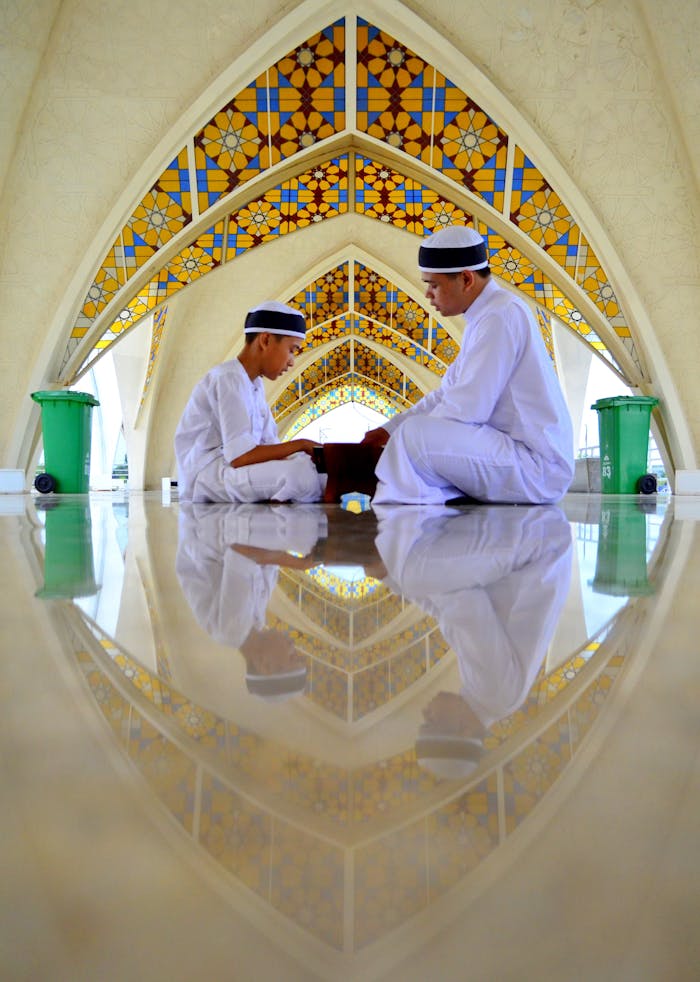 Two people pray in a colorful Indonesian mosque, reflecting devotion and tradition.