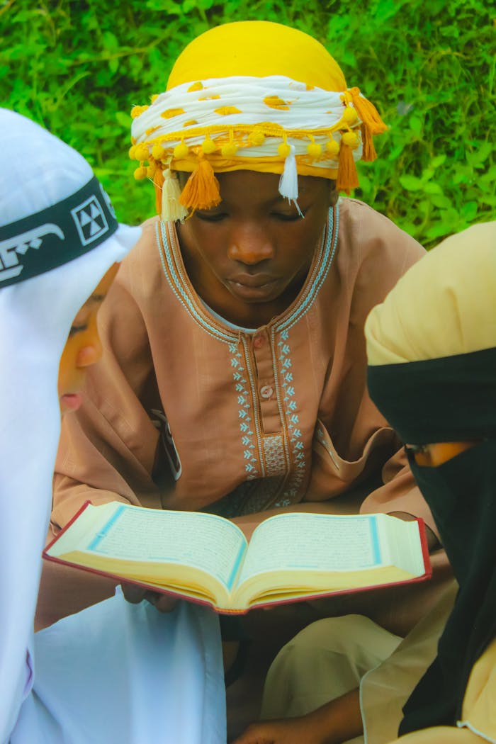 Young adults reading a book together outdoors in Abuja, Nigeria.